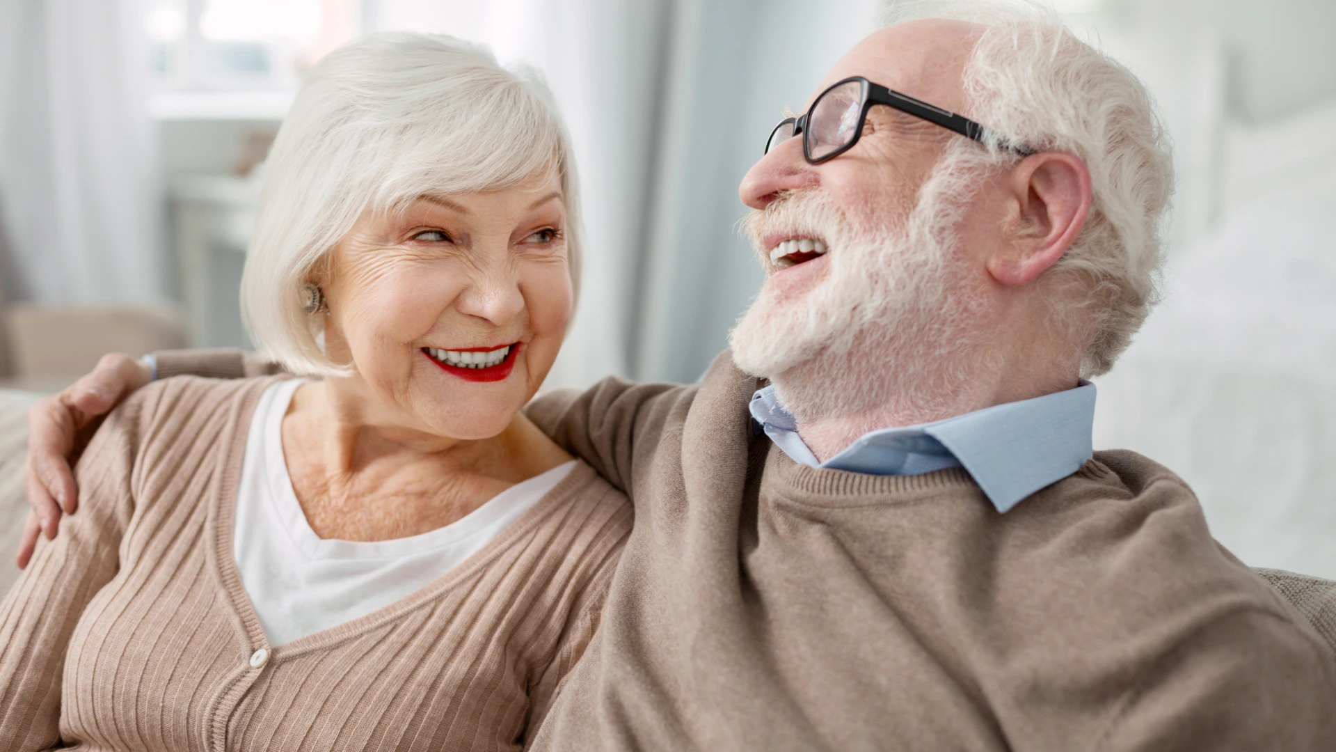 Elderly couple laughing on a couch