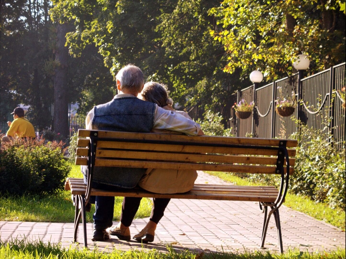 A couple of people sitting on top of a wooden bench.