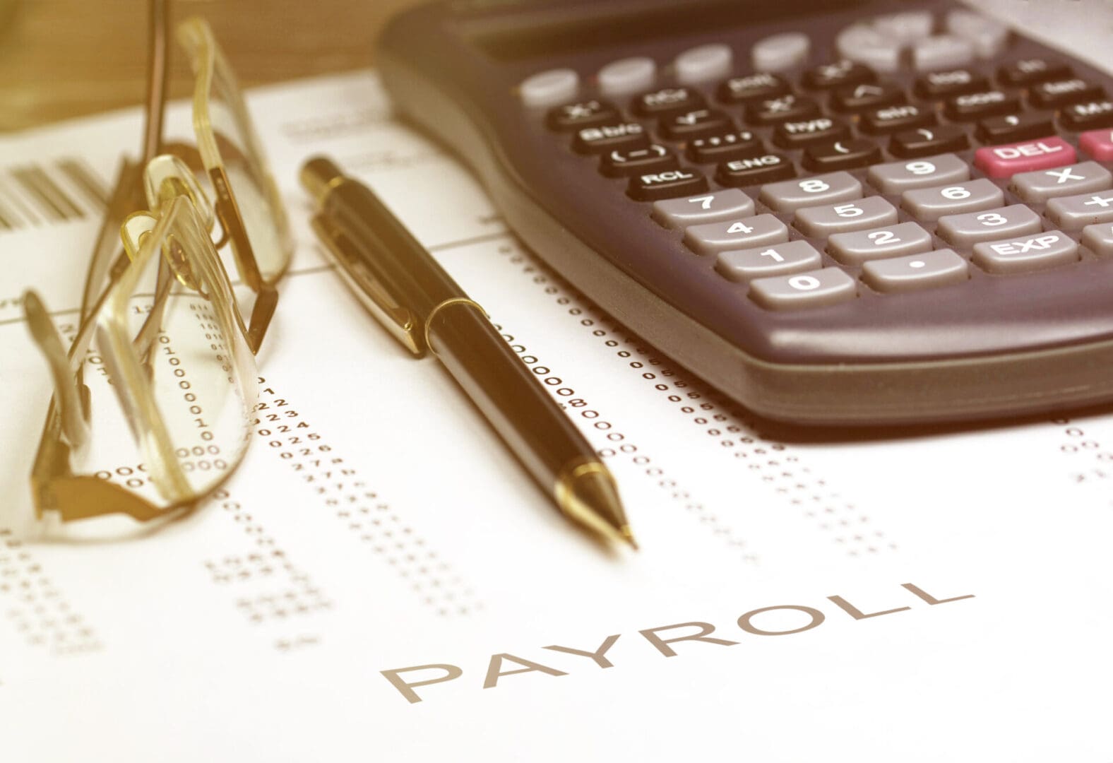 A pen and calculator on top of payroll paperwork.